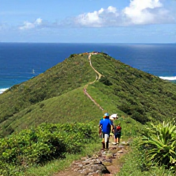 Caribbean Holidays, Antigua Adventure, Visitors hiking through Antigua&rsquo;s green hills above the coastline, with rocky paths, sea views and distant sailboats