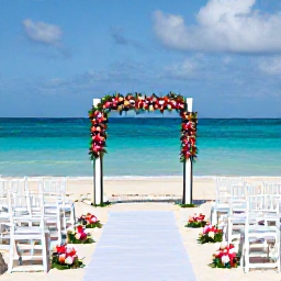 Caribbean Holidays, April Weddings, Elegant beachfront wedding ceremony with white chairs, tropical flowers and turquoise Caribbean water in the background