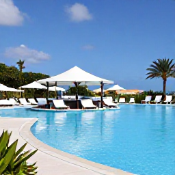 Caribbean Holidays, Aruba Adults Only, Elegant adults-only resort pool in Aruba with swim-up bar, loungers, tropical planting and blue sky