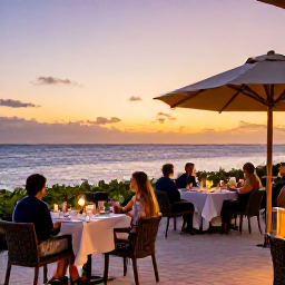 Caribbean Holidays, Aruba Business Class, Elegant beachfront restaurant in Aruba at sunset, with outdoor tables, gentle sea views and diners enjoying a relaxed evening