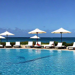 Caribbean Holidays, Aruba in February, Elegant Aruba resort pool overlooking the sea, with a couple relaxing on loungers under clear blue skies