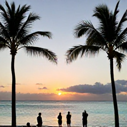 Caribbean Holidays, Aruba Instagram Spots, Palm Beach Aruba at sunset with calm turquoise sea, colourful sky, palm silhouettes and holidaymakers taking photographs