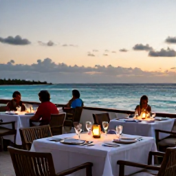 Caribbean Holidays, Aruba Luxury Holidays, A romantic beachfront restaurant in Aruba at sunset, with an elegantly laid table, soft lights and diners overlooking the Caribbean Sea