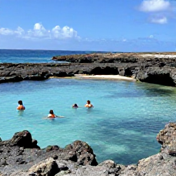 Caribbean Holidays, Aruba Nature Holidays, A calm turquoise natural pool surrounded by dark volcanic rocks on Aruba's coast, with travellers swimming safely nearby