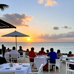 Caribbean Holidays, Aruba Spa Breaks, Sunset over Aruba coastline with a relaxed outdoor restaurant, warm evening light and holidaymakers dining beside the sea