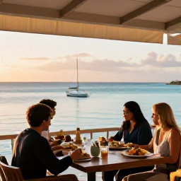 Caribbean Holidays, August All Inclusive, A relaxed beachfront restaurant at sunset in Turks and Caicos, with diners enjoying fresh Caribbean food and views across calm turquoise water