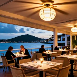 Caribbean Holidays, August Luxury, A stylish restaurant in Gustavia at dusk, with outdoor tables, warm lights, Caribbean harbour views and smartly dressed diners
