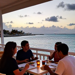 Caribbean Holidays, Bahamas Family Holidays, Family enjoying a relaxed meal at an outdoor restaurant overlooking the sea in Nassau, Bahamas, at sunset
