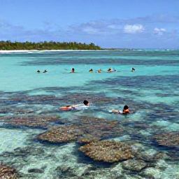 Caribbean Holidays, Bahamas in February, Visitors swimming and snorkelling in clear shallow Bahamian water above a colourful coral reef, with a sunny island shoreline in the background
