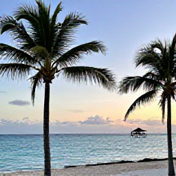 Caribbean Holidays, Bahamas Nature Holidays, A peaceful Bahamian beach at sunset with palm trees, calm turquoise sea and a small eco-friendly lodge in the distance
