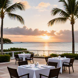 Caribbean Holidays, Barbados Luxury Holidays, Luxury Barbados hotel terrace overlooking a calm Caribbean bay at sunset, with elegant outdoor dining and palm trees