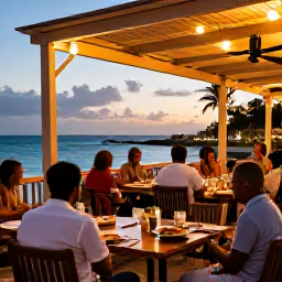 Caribbean Holidays, Barbados Multi-Centre, A relaxed Caribbean evening in Barbados with an outdoor restaurant, local food, warm lights and travellers dining near the sea