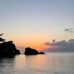 Caribbean Holidays, Bermuda Instagram Spots, Golden sunset over Bermuda&rsquo;s coastline with calm sea, silhouetted rocks and a pastel evening sky