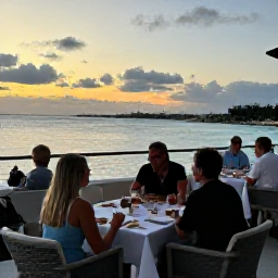 Caribbean Holidays, Bermuda November Breaks, Elegant adults-only Bermuda resort restaurant overlooking the sea at sunset, with an intimate table setting and relaxed diners