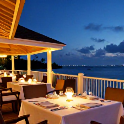 Caribbean Holidays, Cayman Islands Business Class, Elegant waterfront restaurant in the Cayman Islands at dusk, tables prepared for dinner and warm Caribbean lights