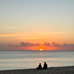 Caribbean Holidays, Cayman Wellness, Peaceful sunset over Seven Mile Beach in Grand Cayman, calm sea, warm sky and a couple relaxing in the distance