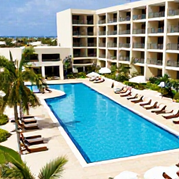 Caribbean Holidays, Curacao All Inclusive, A modern Cura&ccedil;ao all-inclusive resort with a swimming pool, sun loungers, tropical gardens and guests enjoying a relaxed afternoon