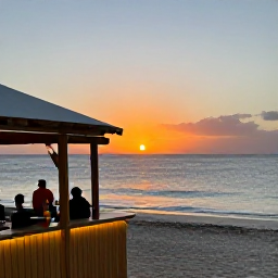 Caribbean Holidays, Curacao Beach Holidays, Visitors enjoying a relaxed sunset at a Cura&ccedil;ao beach bar, with tropical drinks, gentle waves and colourful evening light