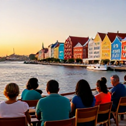 Caribbean Holidays, Cura&ccedil;ao City Breaks, Travellers sitting at a waterside caf&eacute; in Willemstad at sunset, with colourful buildings and boats in the harbour
