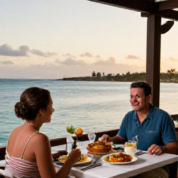 Caribbean Holidays, Cura&ccedil;ao Couples Holidays, Couple dining at an outdoor restaurant overlooking the sea in Cura&ccedil;ao at sunset, with local food and soft evening light
