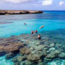 Caribbean Holidays, Curacao December Holidays, Visitors snorkelling above a shallow coral reef in clear blue water near Curacao, with colourful fish and rocky coastline nearby