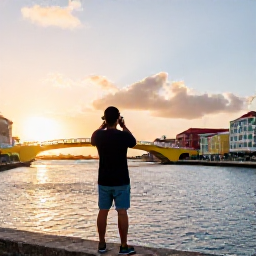 Caribbean Holidays, Cura&ccedil;ao Instagram Spots, A traveller photographing the colourful Queen Emma Bridge and Willemstad waterfront at sunset in Cura&ccedil;ao