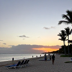 Caribbean Holidays, Dominican Republic Tours, A calm Caribbean beach in Punta Cana at sunset, with loungers, palm trees and travellers enjoying an evening walk