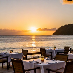 Caribbean Holidays, February Holidays, A Saint Lucia sunset viewed from a beachfront restaurant, with tables prepared for dinner and warm golden light over the sea