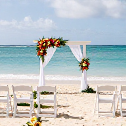 Caribbean Holidays, February Weddings, A beautifully arranged wedding ceremony on a quiet Barbados beach with white chairs, tropical flowers and the Caribbean Sea behind