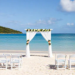 Caribbean Holidays, February Weddings, Elegant beachfront wedding ceremony in the British Virgin Islands, white chairs, simple tropical flowers, calm turquoise sea and blue sky