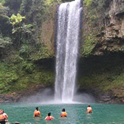 Caribbean Holidays, Grenada Nature Holidays, A tall waterfall flowing into a clear natural pool in Grenada, surrounded by tropical forest and visitors enjoying a peaceful swim