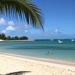 Caribbean Holidays, Guadeloupe Beach Holidays, Traveller enjoying a December beach day in Guadeloupe, swimming in clear water beside palm-fringed sand with small boats offshore