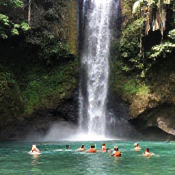 Caribbean Holidays, Guadeloupe Nature, Waterfall surrounded by tropical vegetation in Guadeloupe National Park, with visitors swimming in a clear pool