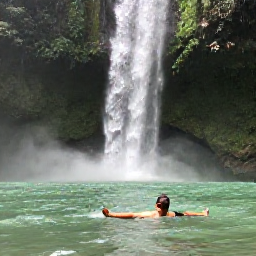 Caribbean Holidays, Jamaica Backpacking July, Backpacker swimming beneath Dunn's River Falls in Jamaica, surrounded by lush green forest and clear water