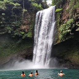 Caribbean Holidays, Jamaica Holidays June, A dramatic Jamaican waterfall surrounded by lush green forest, with visitors swimming in a clear natural pool