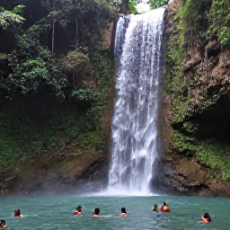 Caribbean Holidays, Jamaica in October, Lush Jamaican waterfall surrounded by tropical greenery, with visitors swimming in a natural pool beneath cascading water