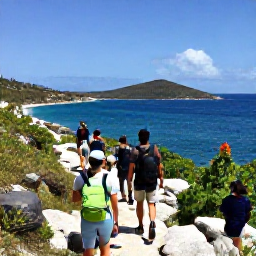 Caribbean Holidays, June Adventures, Hikers walking along a rocky coastal trail with sea views on Virgin Gorda in the British Virgin Islands
