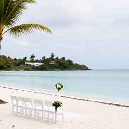 Caribbean Holidays, June Weddings, An elegant seaside wedding ceremony on a British Virgin Islands beach, white chairs, simple flowers, calm turquoise water and palm trees