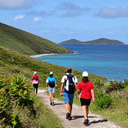 Caribbean Holidays, March Adventures, Hikers walking along a coastal trail on Tortola with green hills, blue sea and distant British Virgin Islands in the background