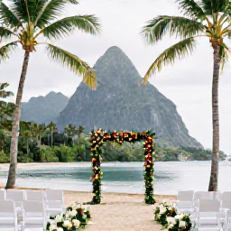 Caribbean Holidays, March Weddings, Elegant tropical wedding ceremony set on a sandy Saint Lucia beach with palm trees, floral decorations and the Pitons in the distance