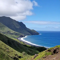 Caribbean Holidays, Montserrat Adventure Holidays, A rugged coastal view of Montserrat in September, with green volcanic hills, dark sand shoreline and bright Caribbean sea under a partly cloudy sky