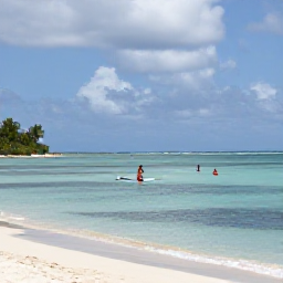 Caribbean Holidays, October Beach Holidays, Visitors swimming and paddleboarding in calm Caribbean water beside a sandy Saint Kitts beach under a partly cloudy October sky