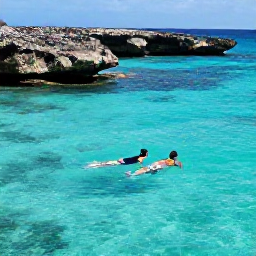 Caribbean Holidays, September Escapes, Couple snorkelling together in a sheltered Cura&ccedil;ao bay with clear turquoise water, tropical fish and rocky coastline