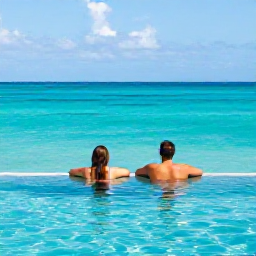 Caribbean Holidays, September Honeymoons, A couple relaxing beside an infinity pool overlooking the turquoise ocean on Providenciales, Turks and Caicos