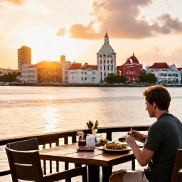 Caribbean Holidays, Solo Curacao March, A relaxed outdoor restaurant table in Willemstad at sunset, with a solo traveller enjoying Caribbean food and a colourful waterfront view