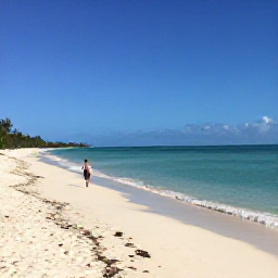 Caribbean Holidays, Solo Turks Caicos, Long white sandy beach at Grace Bay in Turks and Caicos during warm October sunshine, with a lone traveller walking beside calm turquoise water
