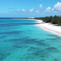 Caribbean Holidays, Turks Caicos July, A bright aerial view of Grace Bay Beach in Turks and Caicos, with clear turquoise water, white sand and a small resort in the distance