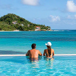 Caribbean Holidays, USVI Couples Holidays, Couple relaxing beside an infinity pool overlooking a turquoise Caribbean bay in the United States Virgin Islands