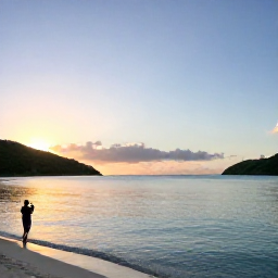 Caribbean Holidays, USVI December Instagram, Sunrise over Magens Bay in St Thomas, United States Virgin Islands, with calm turquoise water, green hills and a person taking a photograph from the beach