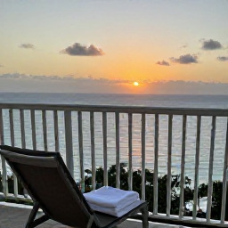 Caribbean Holidays, Virgin Islands Spa, A serene resort balcony overlooking a Caribbean sunset, with a comfortable chair, folded towel and calm ocean beyond